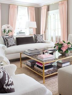 a living room filled with white furniture and lots of pink flowers on the coffee table