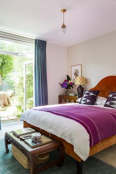 a bedroom with pink walls, blue curtains and a large bed in the middle of it