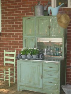 an old green kitchen with pots and pans on the stove top next to a chair