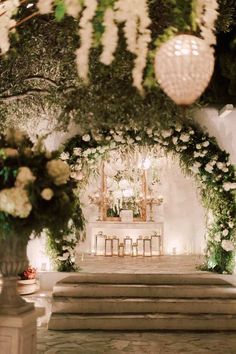 an outdoor ceremony with flowers and greenery on the wall, candles in vases