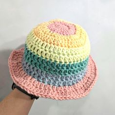 a multicolored crocheted hat is being held by a person's hand