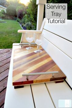 a wooden cutting board sitting on top of a white bench next to a glass vase