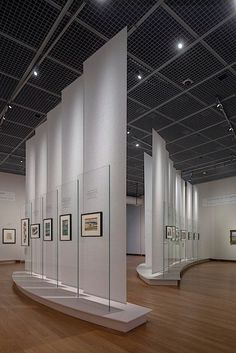 an art gallery with white walls and wooden floors, framed pictures on the wall in glass cases