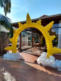 an arch made out of balloons in the shape of stars and clouds on a brick walkway