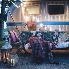 a person laying on the ground in front of a camper with chairs and lights