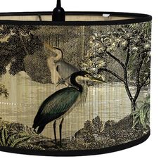 a lamp shade that has a bird on it and trees in the background with leaves