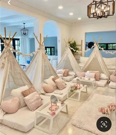 a living room filled with lots of pillows and teepees on top of white couches