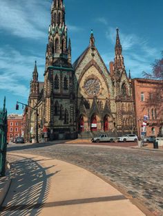 an old church in the middle of a street with cars parked on the side walk