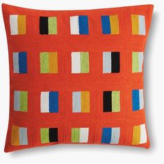 an orange pillow with multicolored squares on it