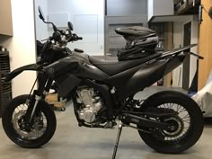 a black motorcycle parked in a garage next to a shelf filled with boxes and other items