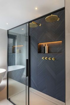 a bathroom with a glass shower door and gold fixtures on the wall, along with a white bathtub