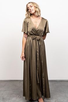 A gorgeous dress for any occasion Earthy olive color Textured satin-like material with subtle sheen Crossover surplice neckline Romantic flutter sleeves Elastic waistband with separate self-tie sash Maxi skirt with left and right leg slits Lined from waist to mid-thigh We recommend sizing up for larger busts Bump and nursing friendly Bekah is 5'10, cup size 34C, size 10 and is wearing size L Trina is 5'6, cup size 32C, size 2 and is wearing size S Green Bridesmaid Dress, Juniper Green, Olive Dress, Baltic Born, Velvet Maxi Dress, Green Bridesmaid, Rust Dress, Satin Maxi, Flattering Dresses