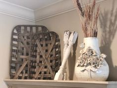 two white vases sitting on top of a mantle