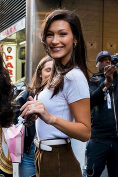 a woman standing in front of a crowd holding onto a pink and white paper bag