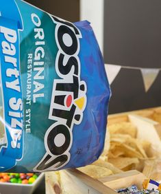 a bag of nachos being held up by a person's hand with chips in the background