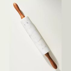 a marble rolling pin with wooden handles on a white surface, viewed from the top