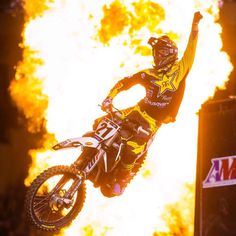 a person on a dirt bike doing a trick in the air with flames behind them