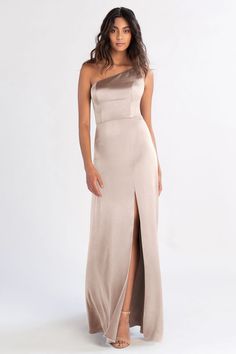 a woman wearing a long dress with one side slited and an asymmetrical neckline