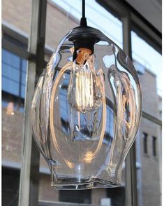 a clear glass light fixture hanging from a ceiling in front of a window with large windows