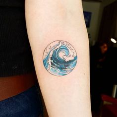 a woman's arm with a blue and white wave tattoo on her left arm