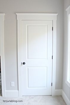 an empty room with two white doors and carpet