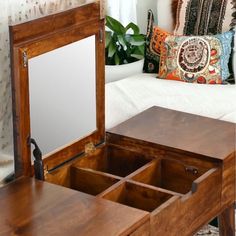 an open wooden jewelry box sitting on top of a table next to a white couch