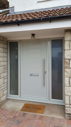 a white door with a welcome mat in front of it on the side of a building