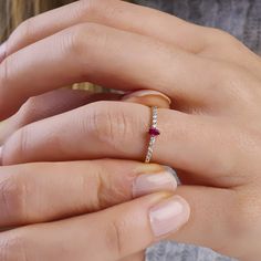 a woman's hand with a diamond and ruby ring on her left finger,