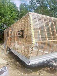 a small house made out of wooden pallets on the ground in front of some trees