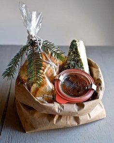 a basket filled with bread and condiments on top of a wooden table next to a pine tree