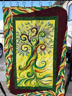 a colorful tree quilt hanging from a rack