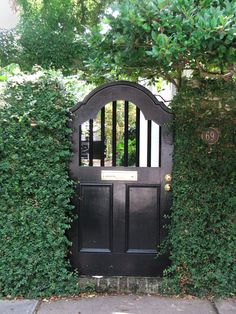 a black gate is surrounded by green plants