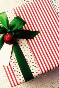 a present wrapped in red and white paper with a green bow on it's side