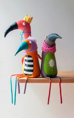 three colorful birds sitting on top of a wooden shelf