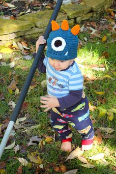 a small child wearing a knitted hat and holding onto a pole with an eyeball on it