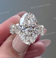 an oval diamond ring with three pear shaped diamonds on the sides and four clawed shoulders