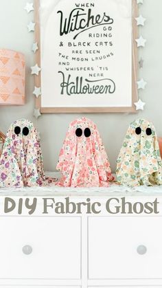 three fabric ghost figurines sitting on top of a white dresser next to a framed sign