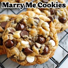 three cookies with chocolate chips and marshmallows are on a cooling rack that says marry me cookies