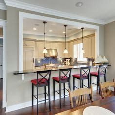 a kitchen with an island and bar stools next to the dining room table in front of it