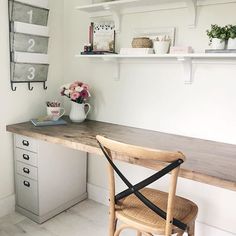 a wooden chair sitting in front of a desk with flowers on it and shelves above