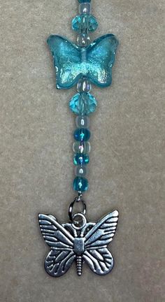 a necklace with a butterfly and beads hanging from it