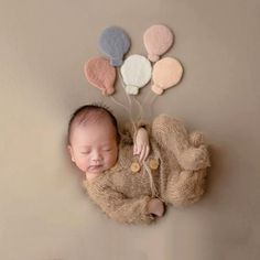 a newborn baby is sleeping with balloons attached to the wall above him and on his back