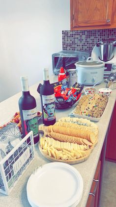 a kitchen counter topped with plates and bowls filled with food next to bottles of wine