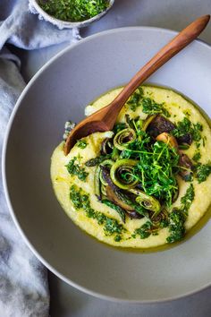 a white bowl filled with food on top of a table next to a wooden spoon