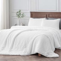 a bed with white comforter and pillows on it