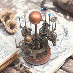 an old clock with gears and pendulums on top of it next to a book