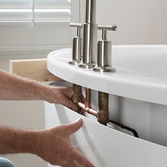 a person fixing a sink in a bathroom