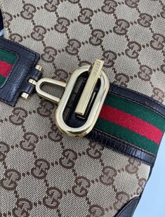 A stunning vintage Gucci Jackie bag made from the iconic GG beige canvas with brown leather trim and gold hardware. This bag also has a bold G closure on the front of the bag. Inside the bag is lined with brown cotton lining and there is a zipped pocket for valuables. This bag is in exceptional vintage condition with some slight wear to the base edges, a true collectors item and comes with the original Gucci dust bag.