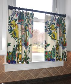 a kitchen window covered in colorful curtains