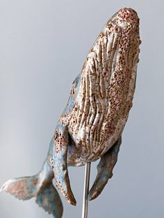 a sculpture of a fish on top of a metal pole with blue and white paint